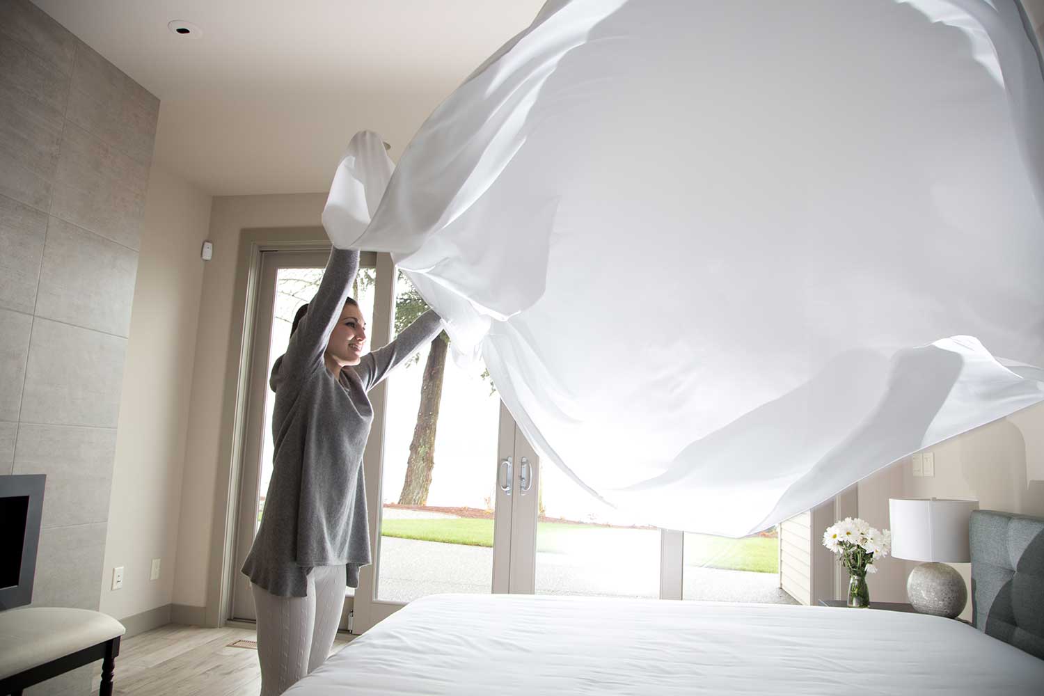 shaking bed sheets after dryer and smoothing on bed